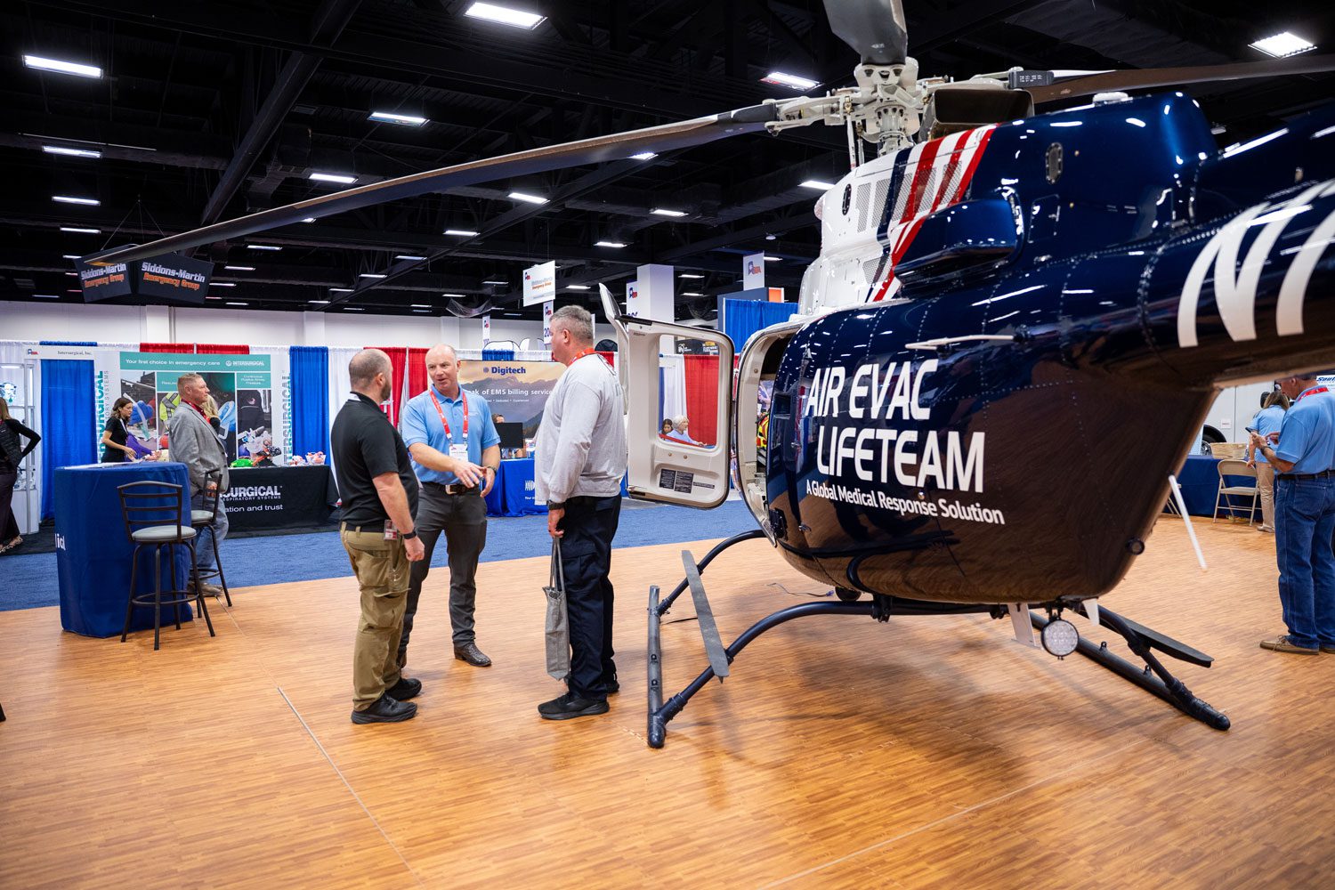 2025-Texas-EMS-Conference-Sunday-95-1500x1000 Exhibitors speaking with attendees in booth with helicopter nearby | Texas EMS Conference